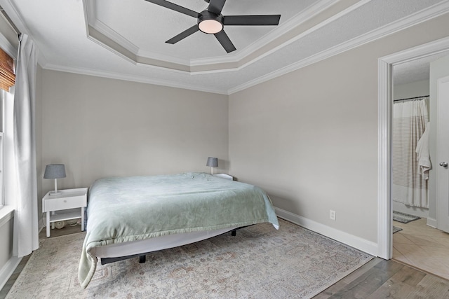 bedroom featuring hardwood / wood-style floors, ceiling fan, a raised ceiling, and ornamental molding