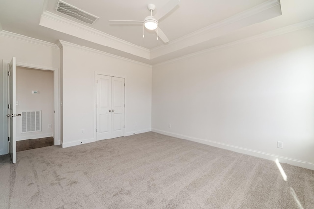 unfurnished bedroom with a tray ceiling, ceiling fan, and carpet