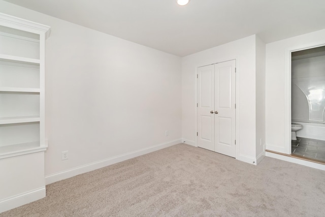 unfurnished bedroom featuring ensuite bath and light carpet