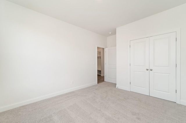 unfurnished bedroom with light carpet and a closet