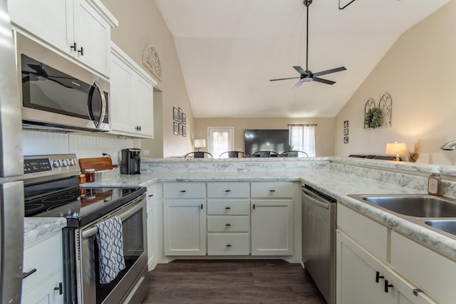 kitchen featuring white cabinets, stainless steel appliances, and vaulted ceiling