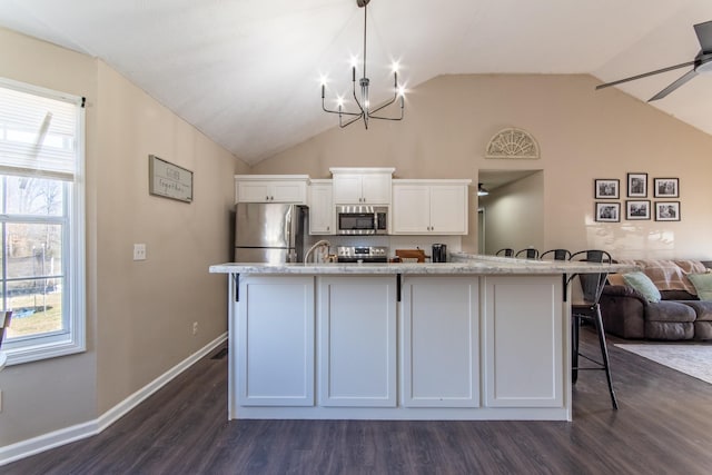 kitchen featuring appliances with stainless steel finishes, ceiling fan with notable chandelier, dark wood-type flooring, decorative light fixtures, and white cabinetry