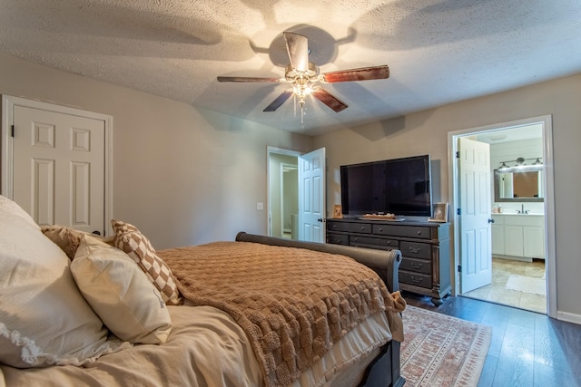 bedroom with ceiling fan, dark hardwood / wood-style floors, a textured ceiling, and ensuite bath