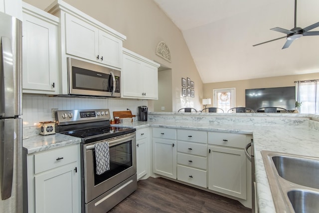 kitchen featuring white cabinets, lofted ceiling, kitchen peninsula, and appliances with stainless steel finishes