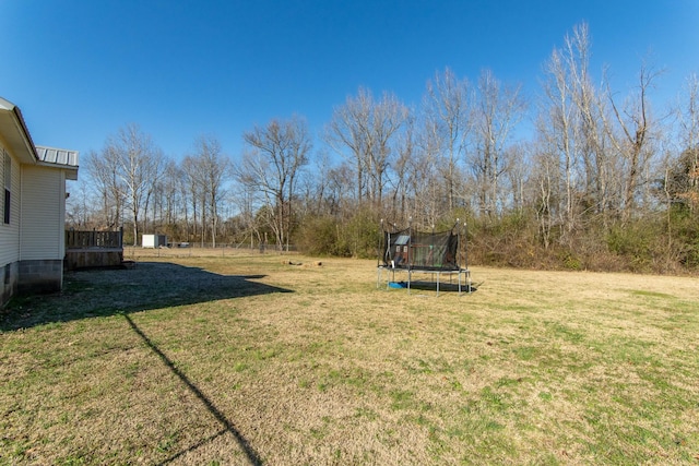 view of yard featuring a trampoline and a wooden deck