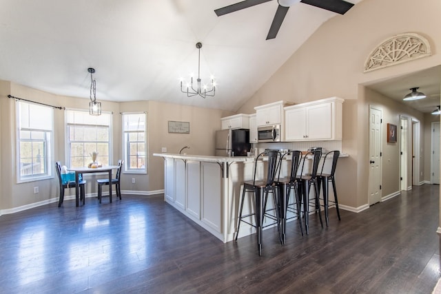 kitchen with white cabinets, decorative light fixtures, a kitchen bar, and appliances with stainless steel finishes