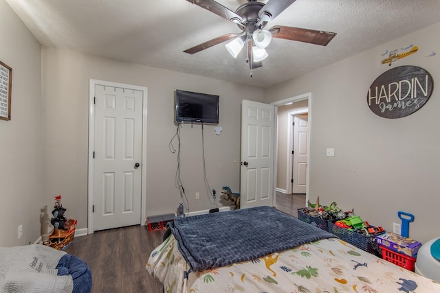 bedroom with ceiling fan, dark wood-type flooring, and a textured ceiling