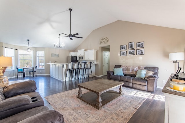 living room with ceiling fan with notable chandelier, dark wood-type flooring, and high vaulted ceiling