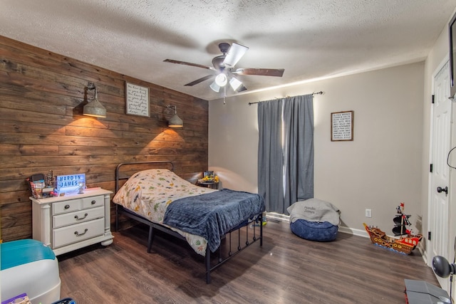 bedroom with wood walls, dark hardwood / wood-style flooring, ceiling fan, and a textured ceiling