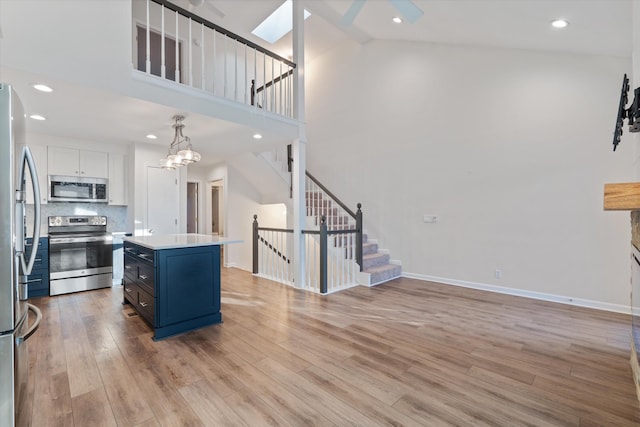 kitchen featuring appliances with stainless steel finishes, backsplash, decorative light fixtures, white cabinets, and a center island