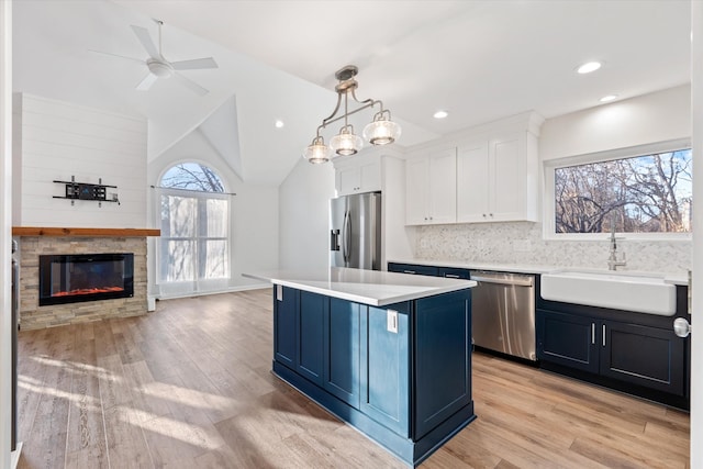 kitchen with pendant lighting, sink, appliances with stainless steel finishes, a kitchen island, and white cabinetry