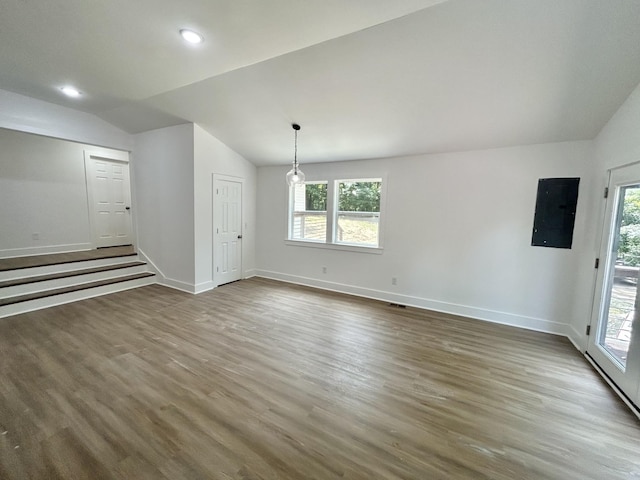 unfurnished living room with dark hardwood / wood-style flooring, electric panel, and lofted ceiling