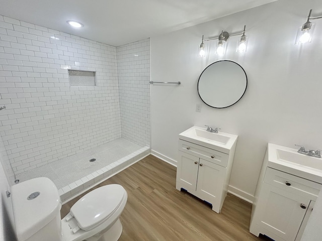 bathroom featuring tiled shower, vanity, wood-type flooring, and toilet