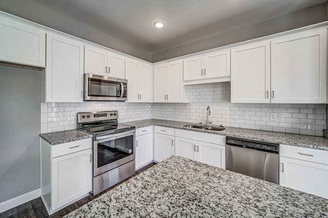 kitchen with white cabinets, appliances with stainless steel finishes, light stone countertops, and sink