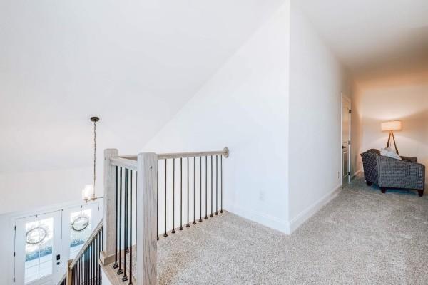 hallway featuring light carpet and vaulted ceiling