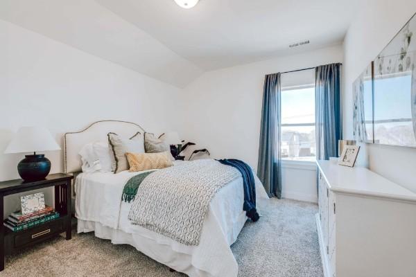 bedroom with light carpet and vaulted ceiling