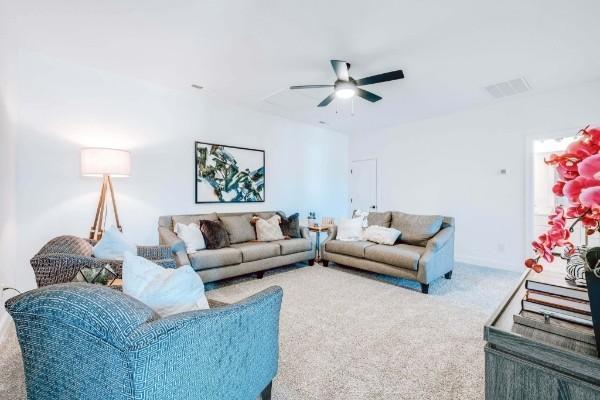 carpeted living room with ceiling fan