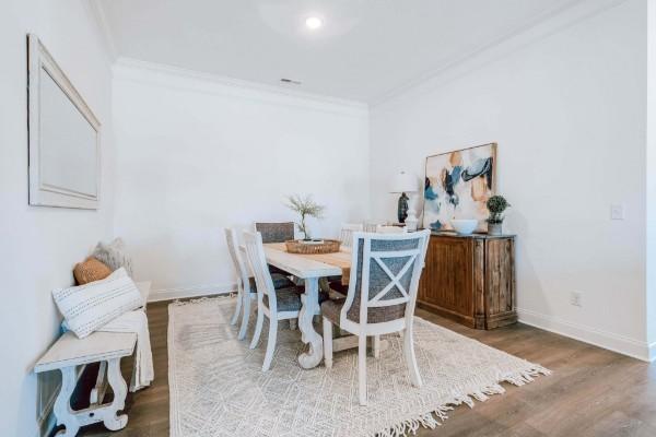 dining space with crown molding and dark wood-type flooring