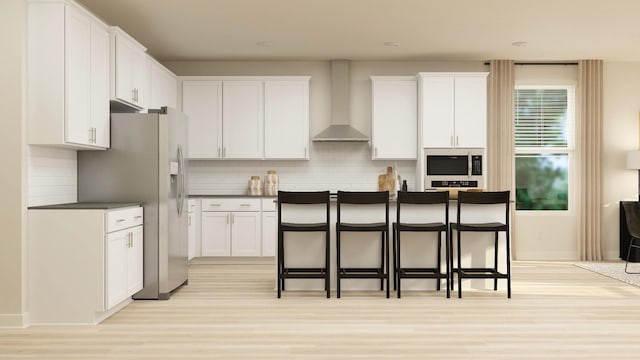 kitchen with a breakfast bar, wall chimney exhaust hood, stainless steel fridge, tasteful backsplash, and white cabinetry