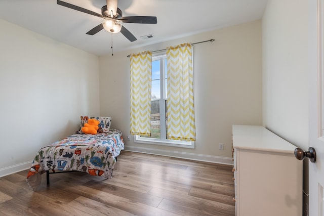 bedroom featuring hardwood / wood-style flooring, ceiling fan, and multiple windows