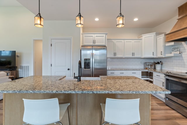 kitchen with decorative backsplash, stainless steel appliances, white cabinetry, and hanging light fixtures