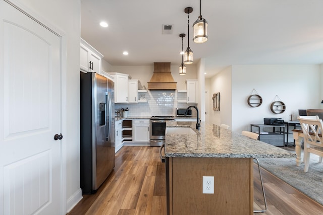 kitchen with hanging light fixtures, appliances with stainless steel finishes, decorative backsplash, white cabinets, and custom exhaust hood