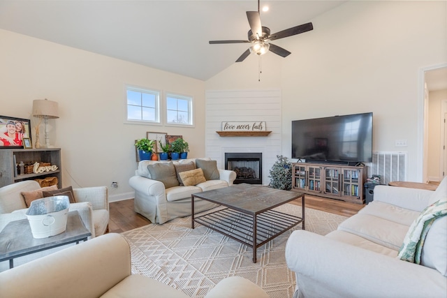 living room with a large fireplace, light hardwood / wood-style flooring, ceiling fan, and lofted ceiling