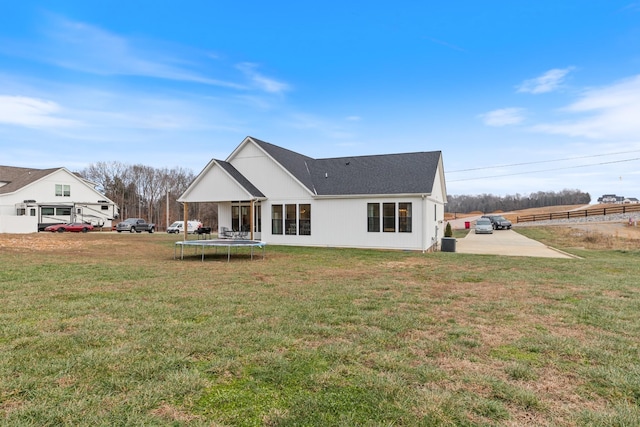 rear view of property with a yard and a trampoline