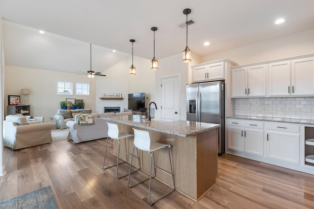 kitchen featuring decorative backsplash, ceiling fan, decorative light fixtures, white cabinets, and an island with sink