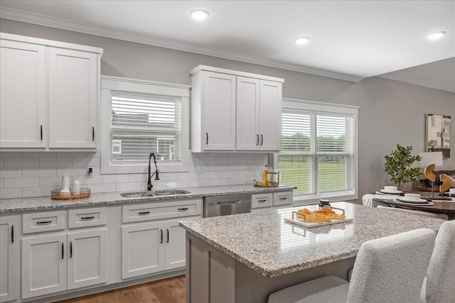 kitchen featuring a kitchen breakfast bar, dishwasher, white cabinets, and sink