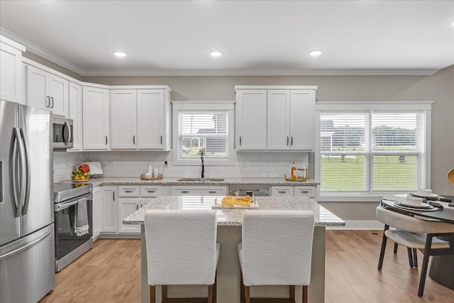 kitchen featuring white cabinetry, light stone countertops, sink, a center island, and stainless steel appliances