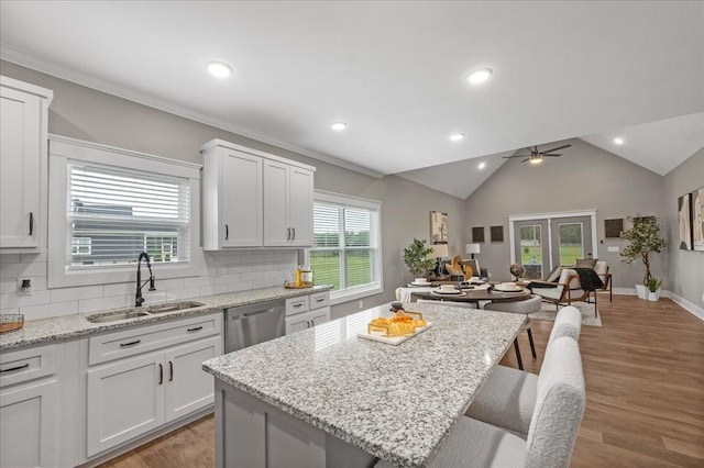 kitchen with ceiling fan, sink, a kitchen breakfast bar, stainless steel dishwasher, and a kitchen island