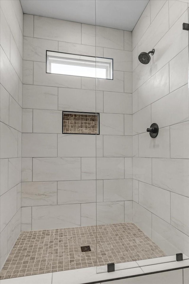 bathroom with a tile shower and a wealth of natural light