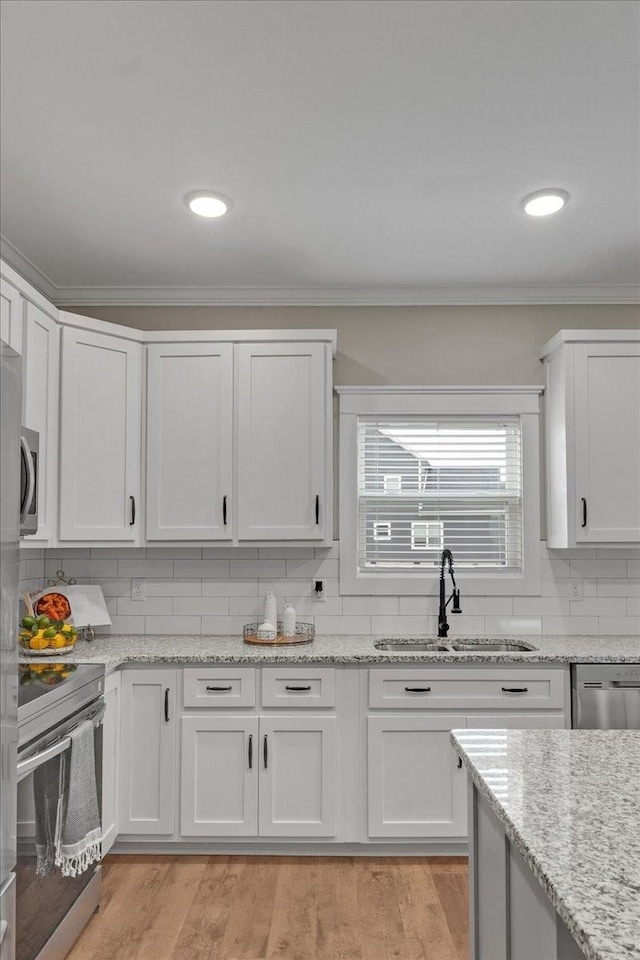 kitchen featuring white cabinetry, sink, light stone countertops, backsplash, and appliances with stainless steel finishes