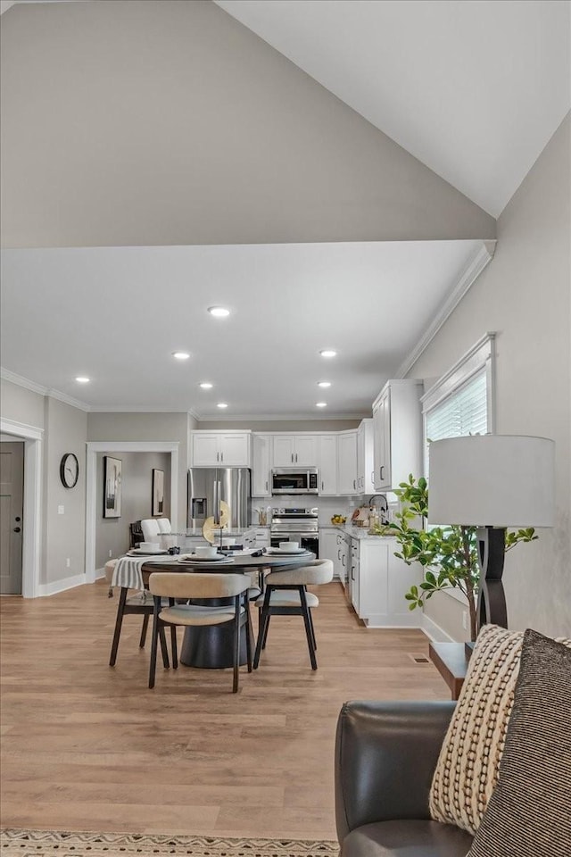 dining area with light hardwood / wood-style flooring, lofted ceiling, and ornamental molding