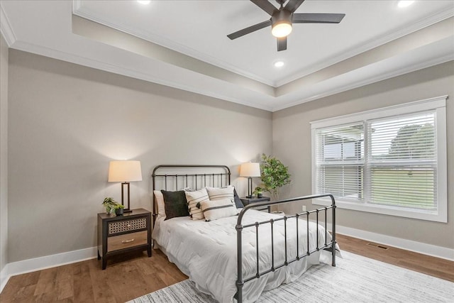 bedroom featuring a raised ceiling, ceiling fan, ornamental molding, and hardwood / wood-style flooring