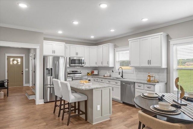 kitchen featuring white cabinets, appliances with stainless steel finishes, a center island, and sink