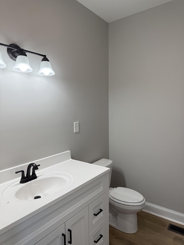 bathroom with toilet, vanity, and hardwood / wood-style flooring