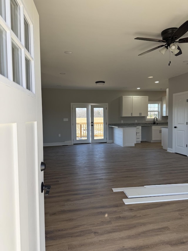 unfurnished living room with ceiling fan, sink, a healthy amount of sunlight, and dark hardwood / wood-style floors