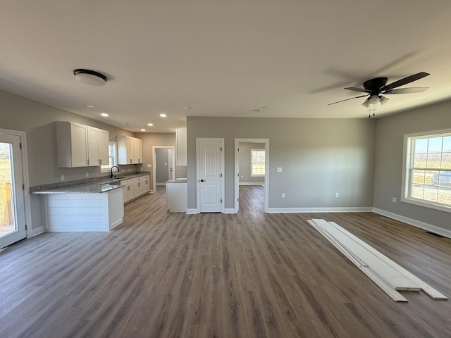 kitchen with ceiling fan, sink, stone counters, light hardwood / wood-style floors, and white cabinetry