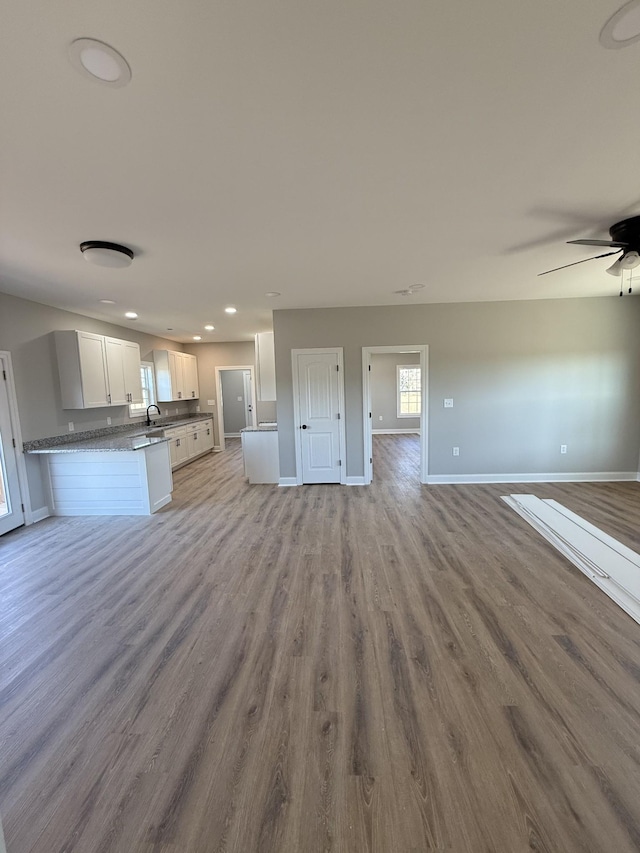 unfurnished living room with ceiling fan, light hardwood / wood-style floors, and sink