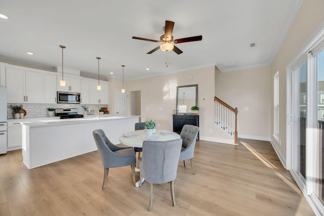 dining space featuring ceiling fan, sink, light hardwood / wood-style floors, and ornamental molding