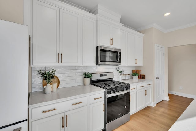 kitchen featuring backsplash, white cabinets, stainless steel appliances, and ornamental molding