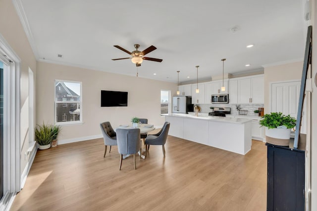 dining room with light wood-type flooring, ceiling fan, and crown molding