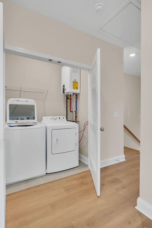 laundry area featuring washing machine and clothes dryer, light wood-type flooring, and water heater