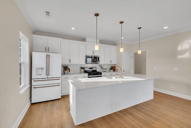 kitchen featuring stainless steel appliances, sink, decorative light fixtures, white cabinetry, and an island with sink