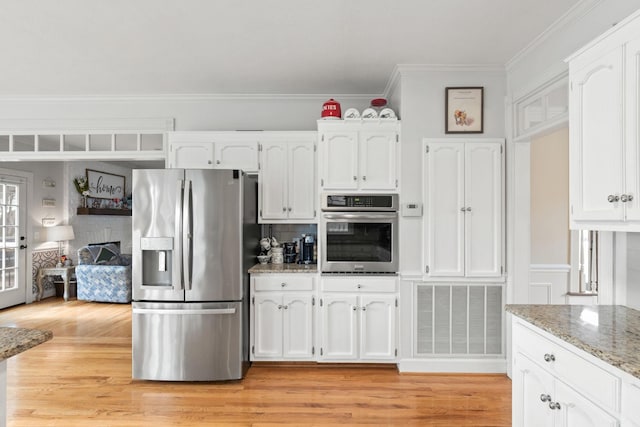 kitchen featuring stainless steel appliances, white cabinets, light wood-type flooring, and light stone counters