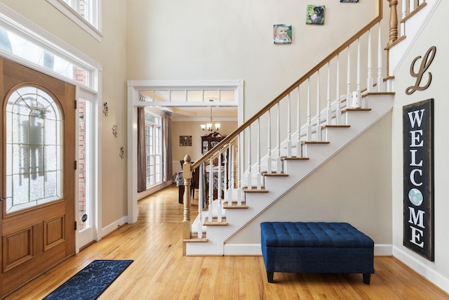 entrance foyer with light wood-type flooring, a healthy amount of sunlight, and a notable chandelier