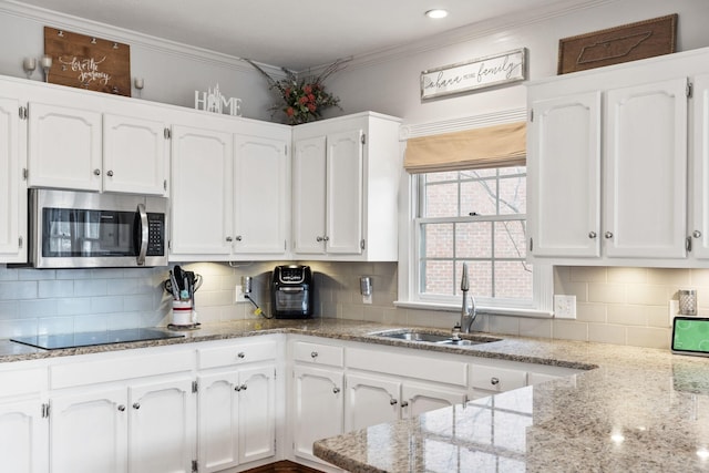 kitchen with sink, white cabinets, light stone counters, tasteful backsplash, and black electric stovetop