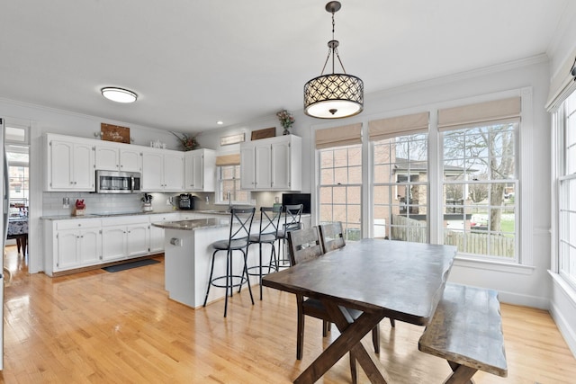 kitchen featuring white cabinets, hanging light fixtures, a kitchen bar, and decorative backsplash